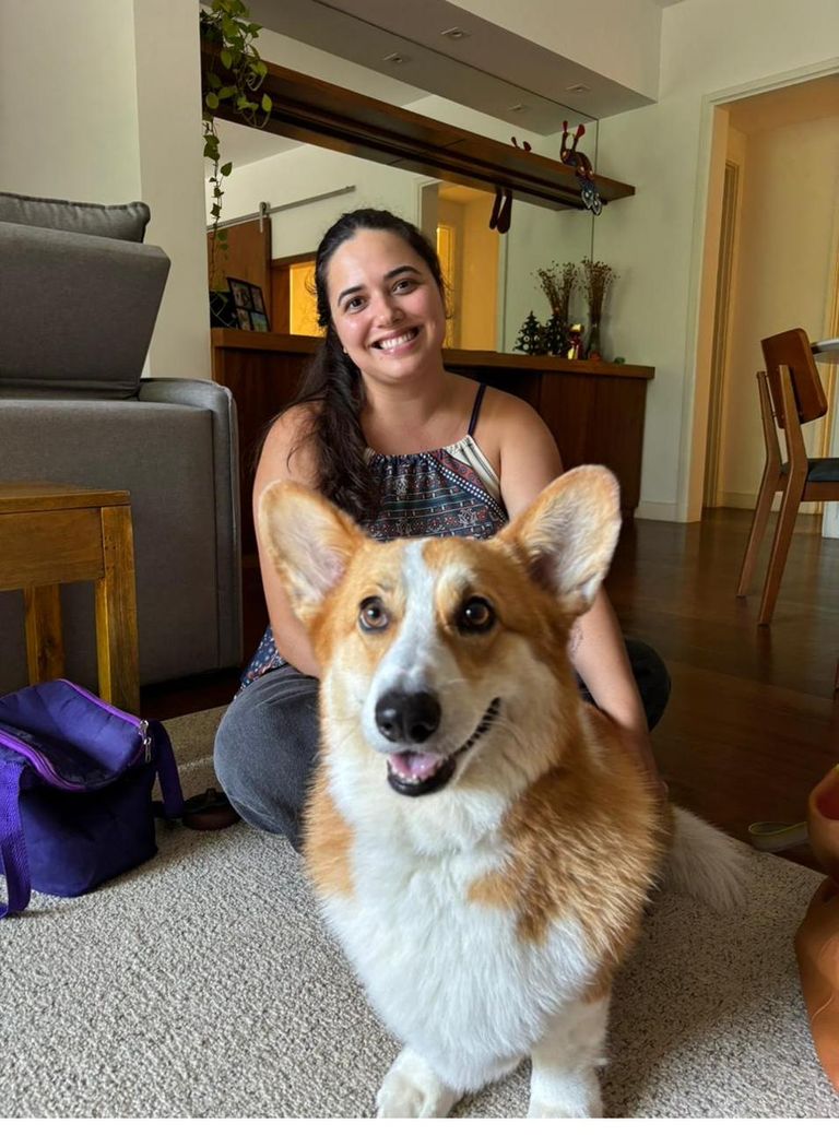 Dra. Marcella Moreira sorrindo ao lado de um cachorro corgi durante atendimento veterinário a domicílio
